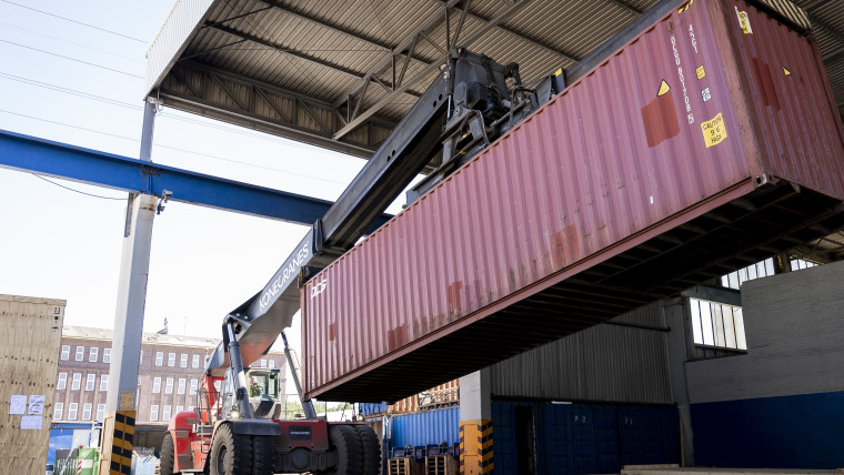 Ein Gabelstapler transportiert einen Container in einer Industrieumgebung.