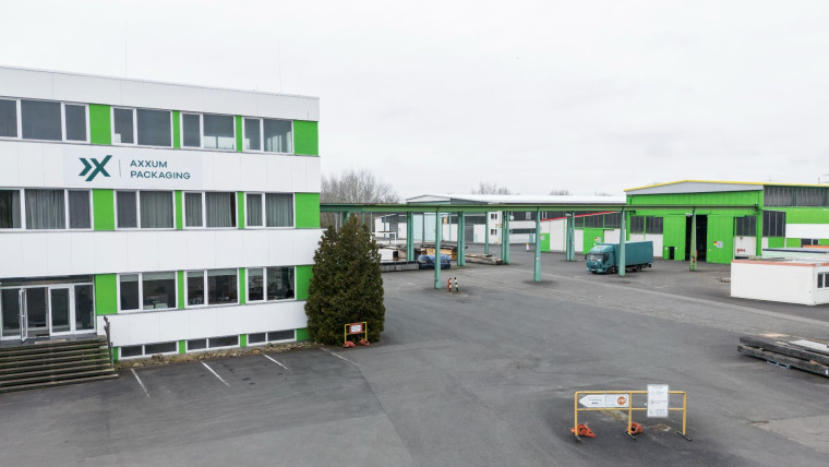 Betriebsgelände von AXXUM Packaging Main-Neckar mit mehrstöckigem Bürogebäude links und mehreren Lagerhallen rechts