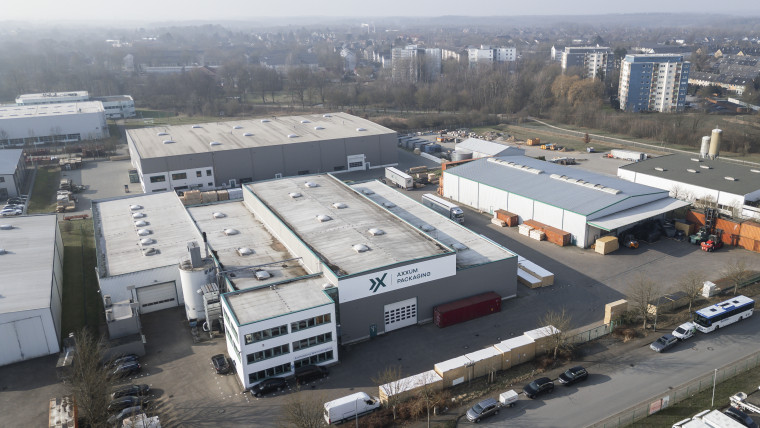 Luftaufnahme einer Fabrik mit zahlreichen Lastwagen auf dem Gelände.